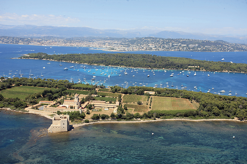 Vue aérienne de l'île Saint-Honorat avec son monastère fortifié, ses vignes et la baie de Cannes en arrière-plan