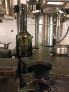 Bouteille de vin de l'Abbaye de Lérins sur la ligne d'embouteillage, en cours de bouchage sous la machine inox