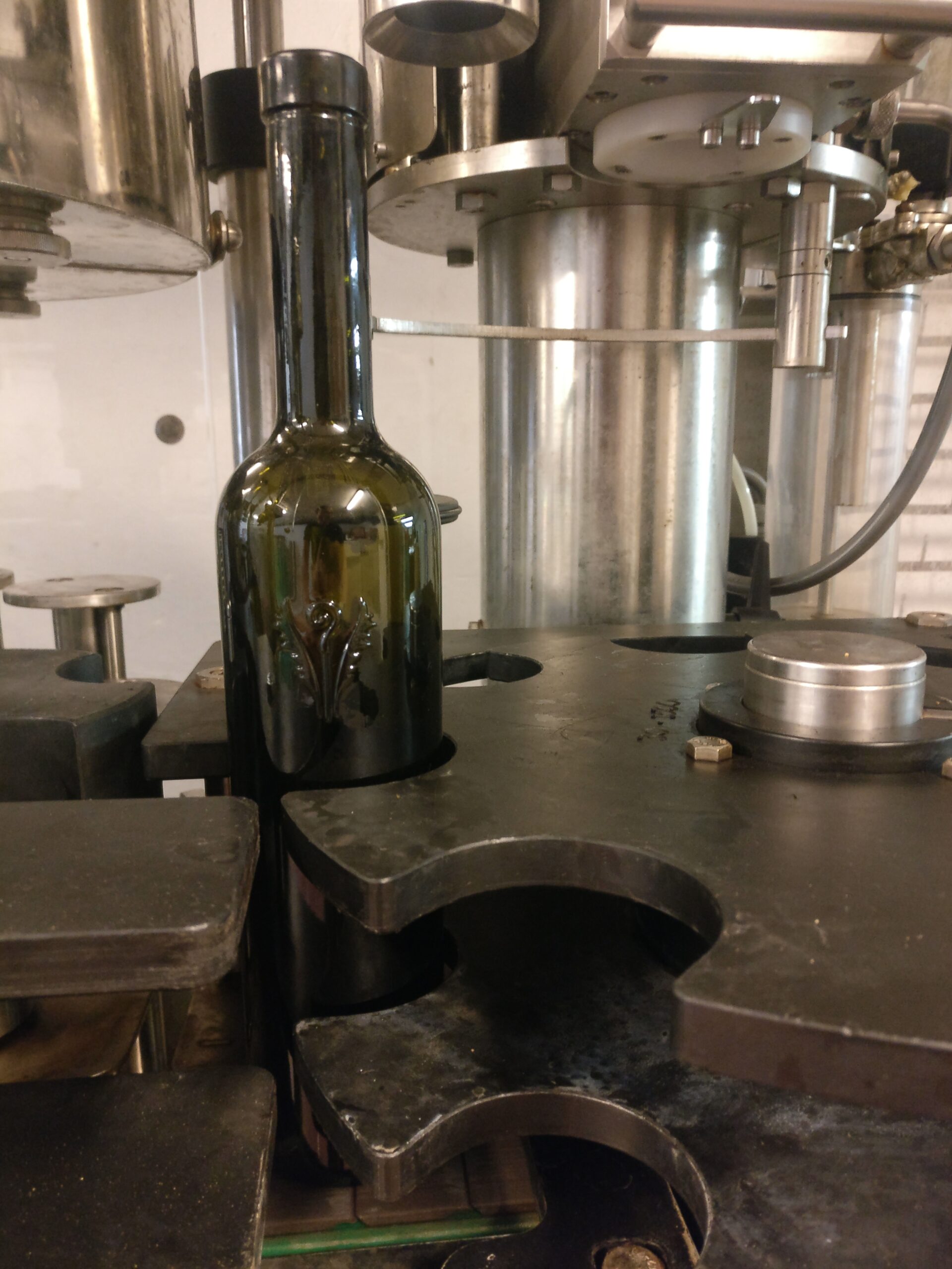 Bouteille de vin de l'Abbaye de Lérins sur la ligne d'embouteillage, en cours de bouchage sous la machine inox