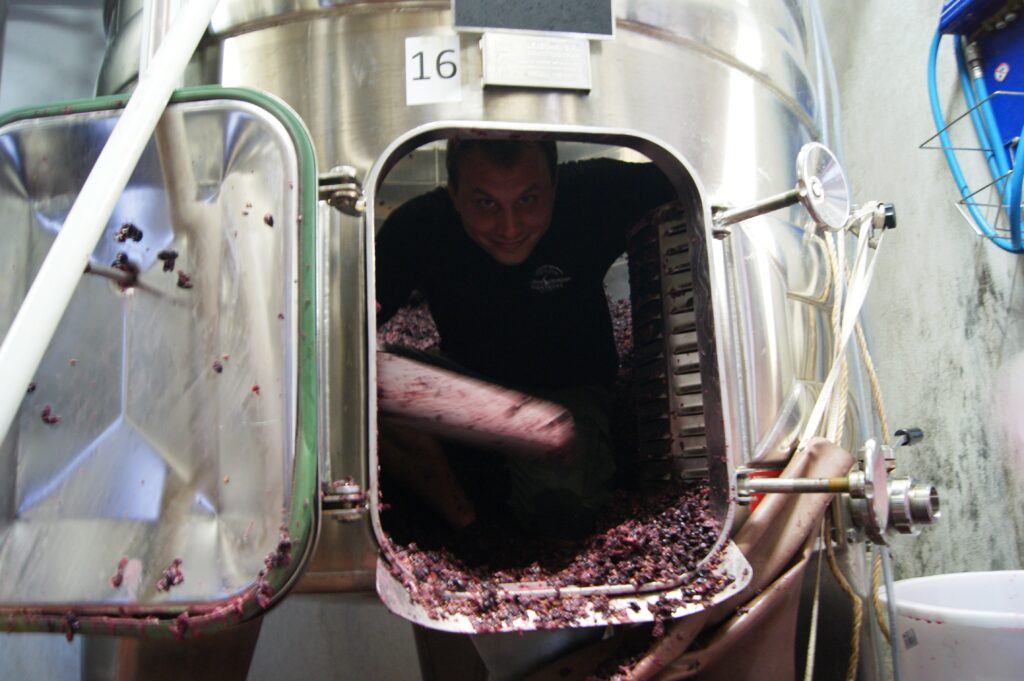 Vigneron nettoyant l'intérieur d'une cuve de vinification en inox après le décuvage à l'Abbaye de Lérins
