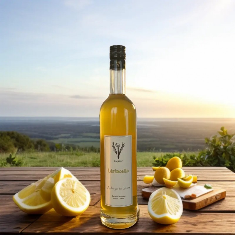 Bouteille de liqueur Lérincello de l'Abbaye de Lérins sur une table en bois, entourée de citrons, face à un paysage de campagne au coucher du soleil